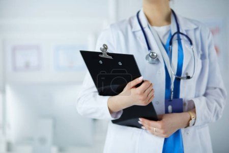 Téléchargez les photos : Femme médecin avec un dossier en uniforme debout dans la salle d'hôpital - en image libre de droit