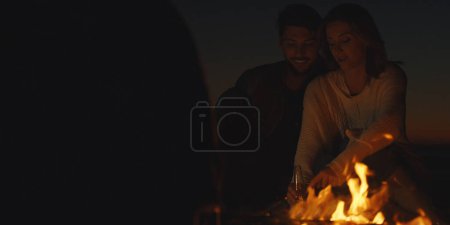 Foto de Pareja disfrutando con amigos por la noche en la playa - Imagen libre de derechos