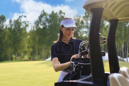 Photo for "Professional woman golf player choosing the golf club from the bag." - Royalty Free Image