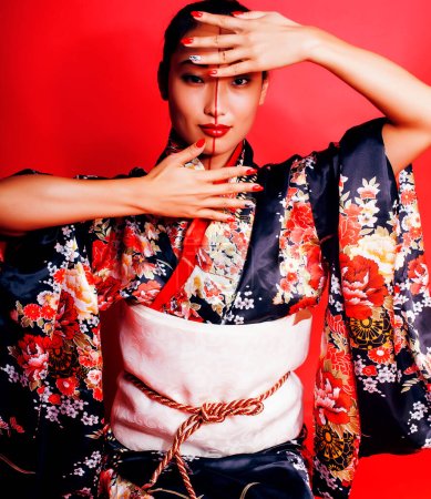 Foto de Joven bastante geisha sobre rojo fondo posando en kimono, oriental - Imagen libre de derechos