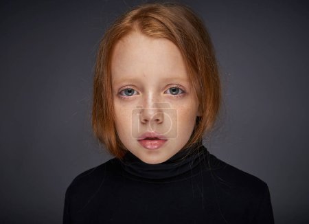 Foto de Chica pelirroja con pecas en la cara en un suéter negro posando - Imagen libre de derechos