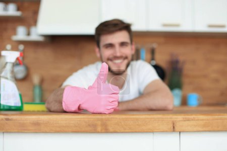 Téléchargez les photos : Jeune homme beau et souriant nettoyage cuisine moderne. - en image libre de droit