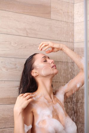 Foto de Joven hermosa mujer bajo la ducha en el baño. - Imagen libre de derechos