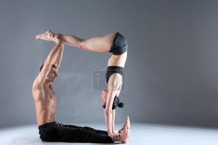 Photo for Young couple practicing acro yoga on mat in studio together. Acroyoga. Couple yoga. Partner yoga. - Royalty Free Image