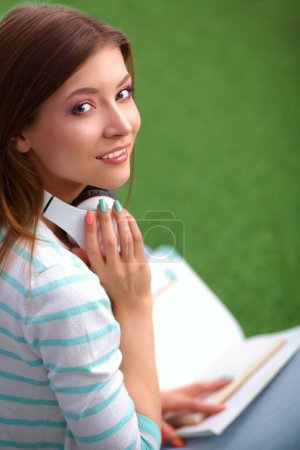 Téléchargez les photos : Femme écoutant la musique assise sur l'herbe - en image libre de droit