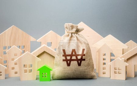 Photo for South korean won money bag and a city of house figures. City municipal budget. Buying real estate, fair price. Investments. Cost of living. Property tax. Development, renovation of buildings. - Royalty Free Image