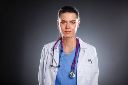 Téléchargez les photos : Jeune médecin femme avec stéthoscope isolé sur gris - en image libre de droit
