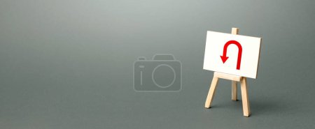 Photo for Easel with red arrow turning back. Tactical retreat for redeployment. Avoiding problems, reducing risks. Uncertainty, lack of purpose. Low discipline. Change plans, circumstances. Finding another way. - Royalty Free Image