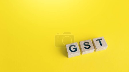 Bloques con letras GST (Goods and Services Tax) sobre fondo amarillo. Política financiera del Estado para regular las normas de recaudación de impuestos y reducir la carga burocrática. Inversiones, facilidad para hacer negocios.