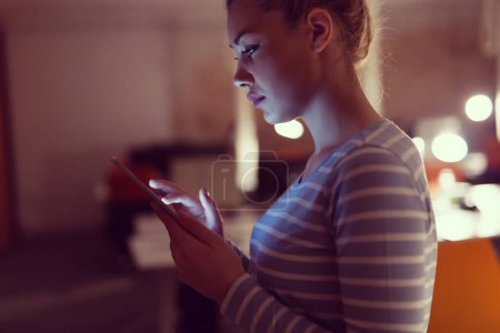 Foto de Mujer trabajando en tableta digital en la oficina nocturna - Imagen libre de derechos