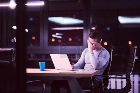 Téléchargez les photos : Homme travaillant sur ordinateur portable dans le bureau sombre - en image libre de droit