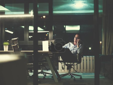 Foto de "hombre de negocios usando el teléfono móvil en la oficina oscura
" - Imagen libre de derechos