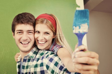 Photo for Young couple painting wall at new home - Royalty Free Image