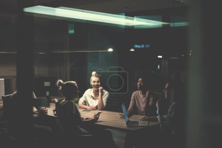 Téléchargez les photos : Équipe multiethnique d'affaires de démarrage dans le bureau de nuit - en image libre de droit