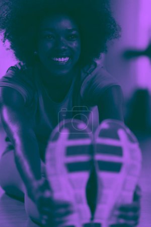 Photo for Woman in a gym stretching and warming up before workout - Royalty Free Image