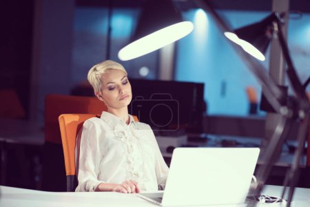 Téléchargez les photos : Femme travaillant sur ordinateur portable dans le bureau de démarrage de nuit - en image libre de droit