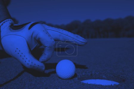 Téléchargez les photos : Main de l'homme mettant balle de golf dans le trou - en image libre de droit