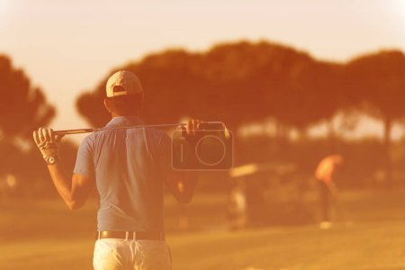 Téléchargez les photos : Golfeur de retour au parcours regardant au trou dans la distance - en image libre de droit
