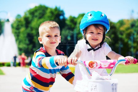 Téléchargez les photos : Garçon et fille dans le parc apprendre à faire du vélo - en image libre de droit