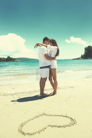 Téléchargez les photos : Couple romantique amoureux s'amuser sur la plage avec coeur dessin sur sable - en image libre de droit