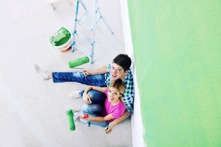 Téléchargez les photos : Heureux jeune couple se détendre après avoir peint dans une nouvelle maison - en image libre de droit