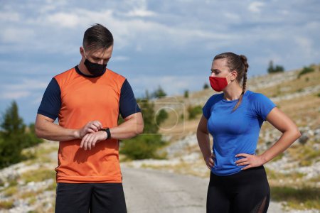 Photo for Couple of running in nature wearing mask having a break - Royalty Free Image