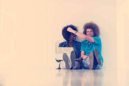 Photo for Multiethnic couple sitting on the floor with a laptop and tablet - Royalty Free Image