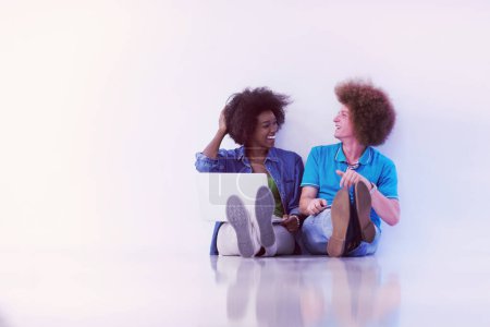 Téléchargez les photos : Couple multiethnique assis sur le sol avec un ordinateur portable et tablette - en image libre de droit