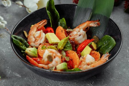 Photo for "Shrimps salad with cherry tomatoes, cucumeber, avocado, lettuce and pomegranate on dish. Healthy seafood concept. Tasty grilled prawn shrimp and mix vegetable salad on black, top view" - Royalty Free Image