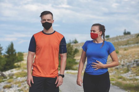 Téléchargez les photos : Couple de courir dans la nature portant un masque ayant une pause - en image libre de droit