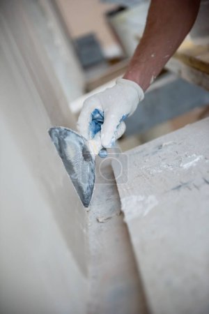 Téléchargez les photos : Travailleur de la construction plâtrage sur les murs de gypse - en image libre de droit