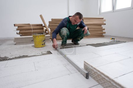 Foto de "trabajador que instala las baldosas de efecto madera cerámica en el suelo" - Imagen libre de derechos