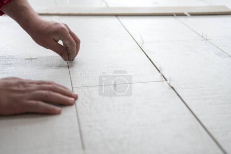 Photo for "worker installing the ceramic wood effect tiles on the floor" - Royalty Free Image