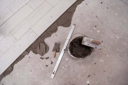 Foto de "Baldosas de efecto madera de cerámica y herramientas para el azulejo en el suelo" - Imagen libre de derechos