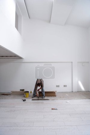 Photo for Worker installing the ceramic wood effect tiles on the floor - Royalty Free Image