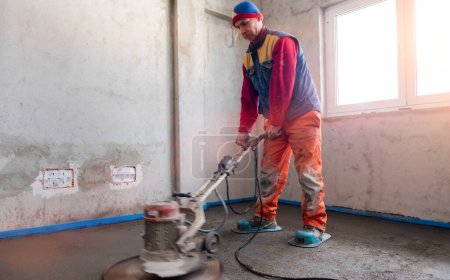 Téléchargez les photos : Travailleur effectuant et polissant sable et plancher de chape de ciment - en image libre de droit