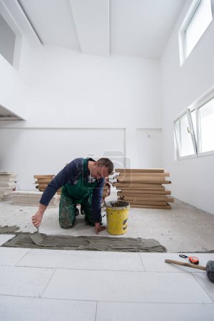 Foto de Trabajador que instala las baldosas de efecto madera cerámica en el suelo - Imagen libre de derechos
