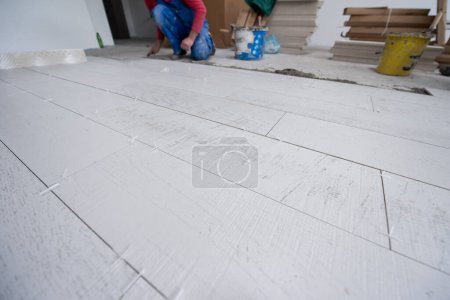 Foto de Trabajador que instala las baldosas de efecto madera cerámica en el suelo - Imagen libre de derechos