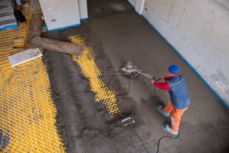 Photo for Worker performing and polishing sand and cement screed floor - Royalty Free Image