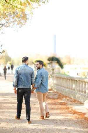 Téléchargez les photos : Vue arrière de deux gays caucasiens marchant dans le parc et se tenant la main. - en image libre de droit