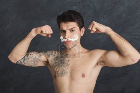 Téléchargez les photos : Jeune homme tatoué sexy avec des moustaches de mousse - en image libre de droit