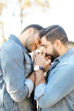 Photo for Portrait of happy gays holding hands and wearing jeans shirts. - Royalty Free Image