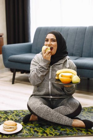Foto de Mujer árabe elegir entre una alimentación saludable y poco saludable. - Imagen libre de derechos