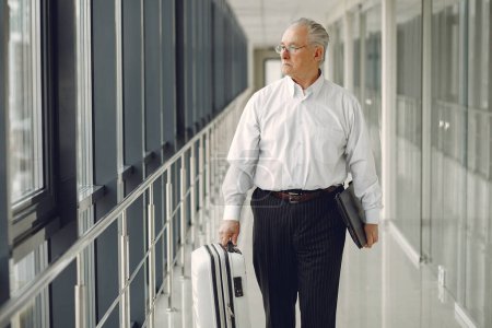 Photo for Elegant old man at the airport with a suitcase - Royalty Free Image