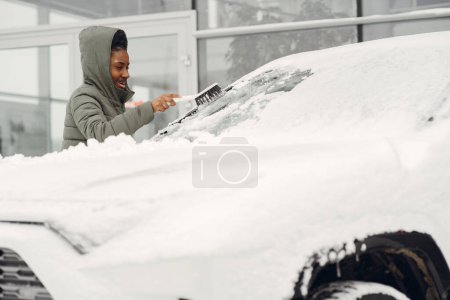 Téléchargez les photos : Femme enlevant la neige du pare-brise de voiture - en image libre de droit