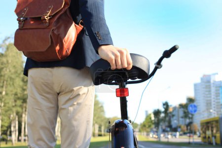Téléchargez les photos : Un jeune homme d'affaires confiant marche à vélo dans la rue en ville - en image libre de droit