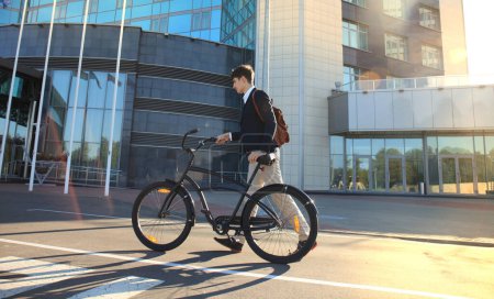 Foto de Joven empresario seguro paseando en bicicleta por la calle de la ciudad - Imagen libre de derechos