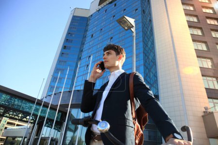 Téléchargez les photos : Jeune homme d'affaires avec vélo et smartphone dans la rue de la ville - en image libre de droit
