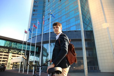 Téléchargez les photos : Un jeune homme d'affaires confiant marche à vélo dans la rue en ville - en image libre de droit