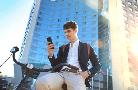 Foto de Joven hombre de negocios con bicicleta y smartphone en la calle de la ciudad - Imagen libre de derechos